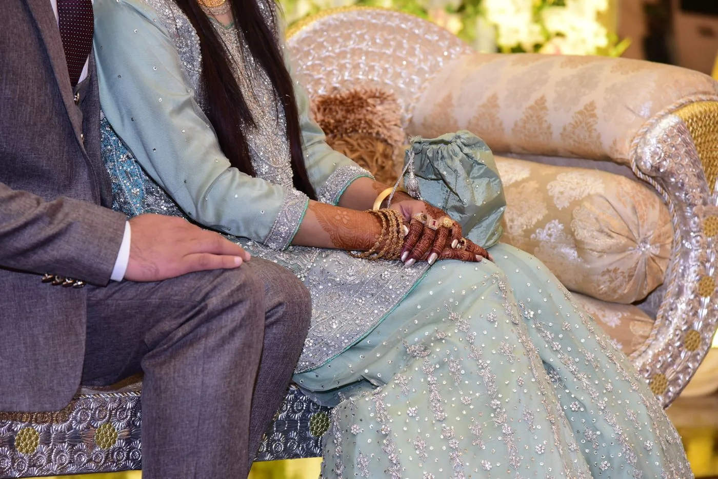 Henna-decorated hands and traditional wedding attire at a celebration in Sialkot