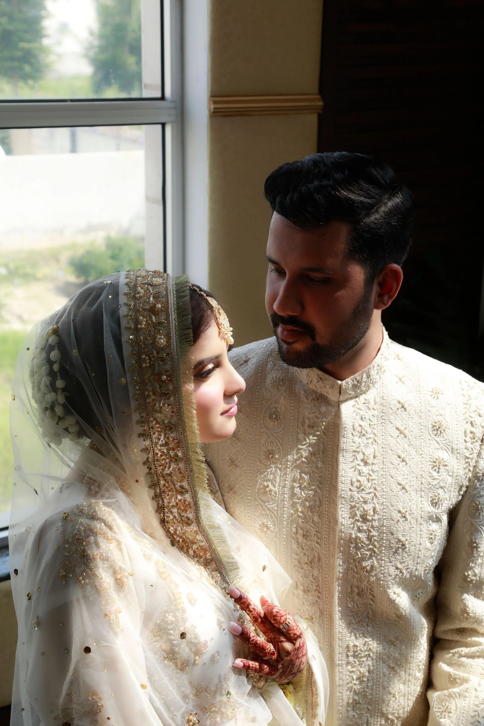 A bride and groom sharing a quiet moment by a window in Lahore
